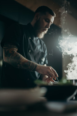 Man preparing food in a commercial kitchen with fresh ingredients on the counter