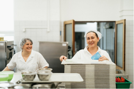 Kitchen staff preparing trays in a commercial kitchen, demonstrating organized workflow and adaptable food preparation
