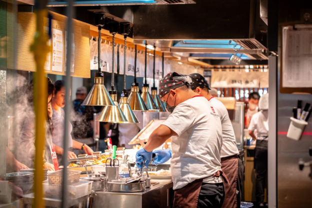 Kitchen staff preparing meals in a busy commercial kitchen focused on efficient workflow and organized food stations