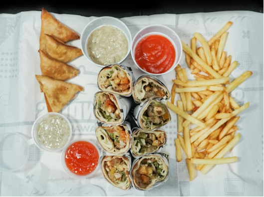 This image shows a balanced spread of golden fries, savory wraps, and crispy sides served with classic dipping sauces