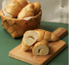 This photo shows croissants and bread resting on wooden board and basket