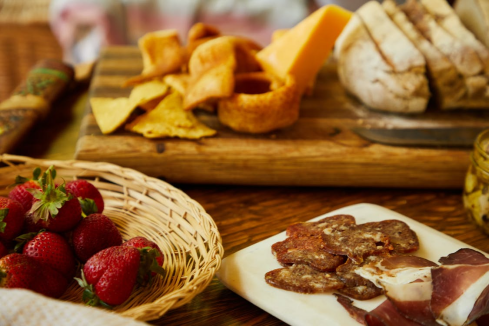 Table with assorted cold cuts, strawberries, cheeses, and snack items, ready for serving in a restaurant or catering setup
