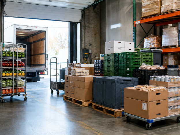 Stacked food distribution crates and boxes on a warehouse loading dock ready for delivery