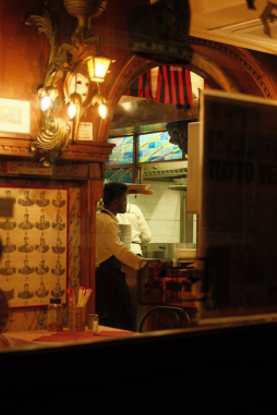 Outdoor restaurant scene at night with diners enjoying food under warm lights
